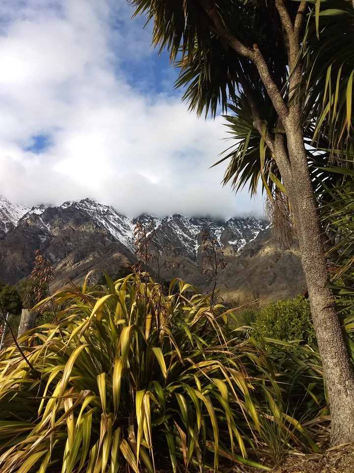 Mountains with sparse vegetation under a cloudy sky.