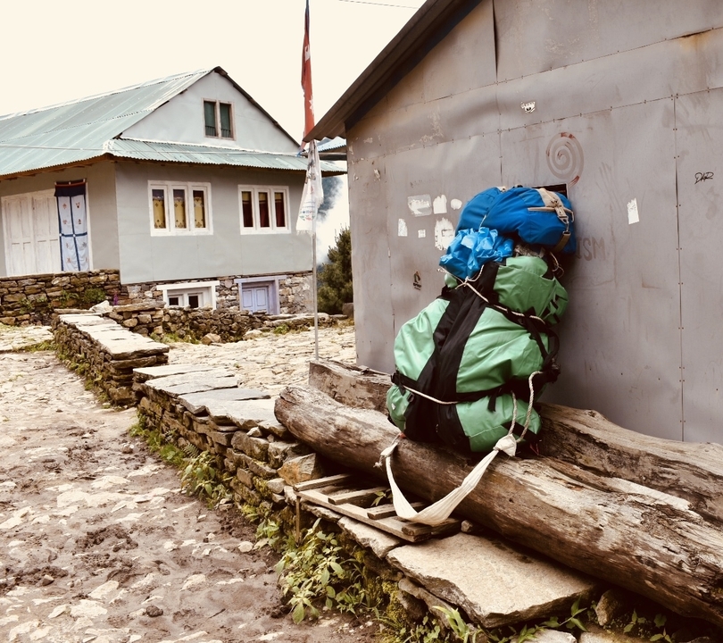 Backpack secured against a wall in a mountainous village.
