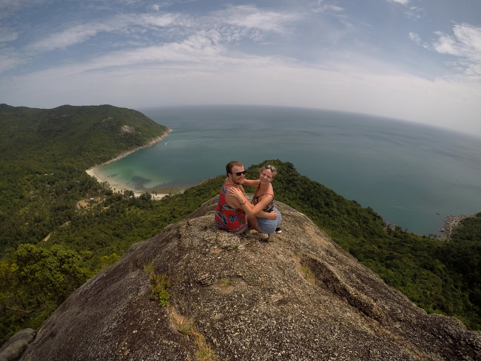 Couple sitting on a rock enjoying a panoramic view of the ocean.