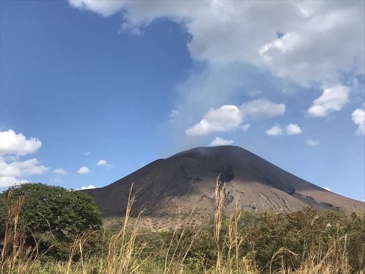 Volcano emitting smoke against a clear sky.