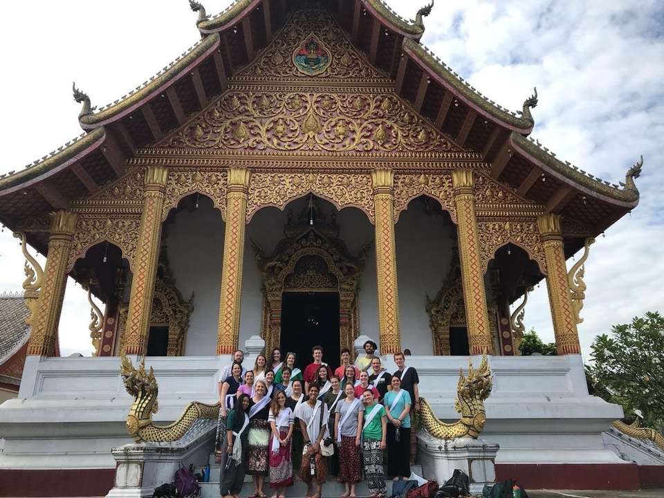 Group of people in front of a large, ornate temple.