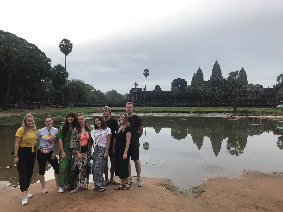 Group of people posing in front of Angkor Wat near reflection pool