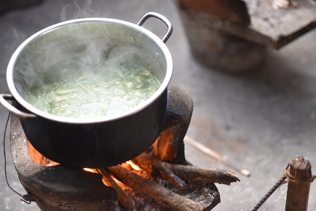 A pot on a stove with steam visible.