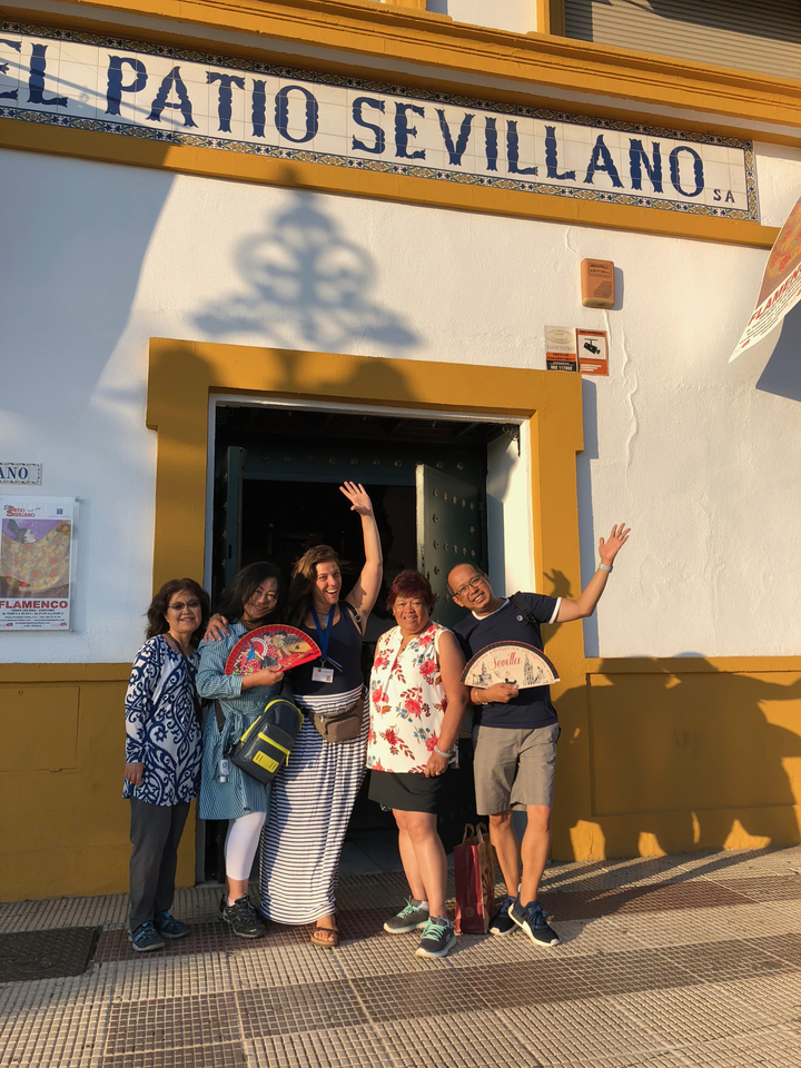 Group of people posing happily with fans in front of a building.