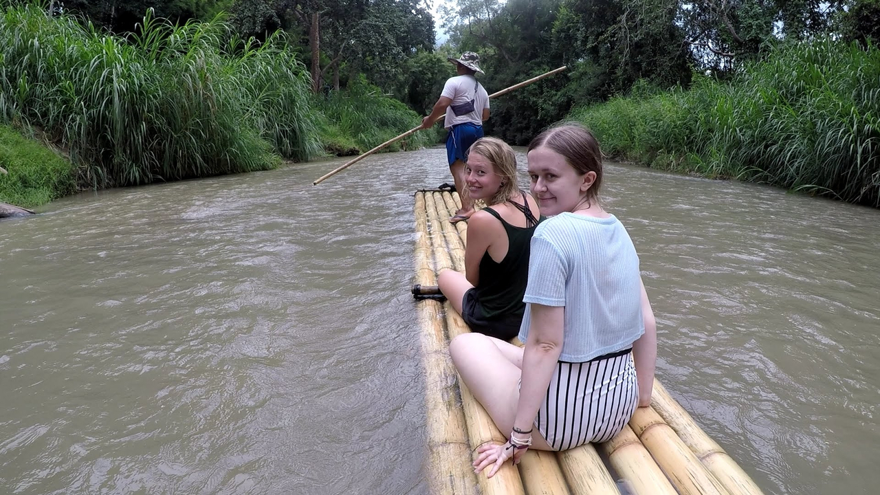 Deux femmes assises sur un radeau de bambou naviguant sur une rivière.