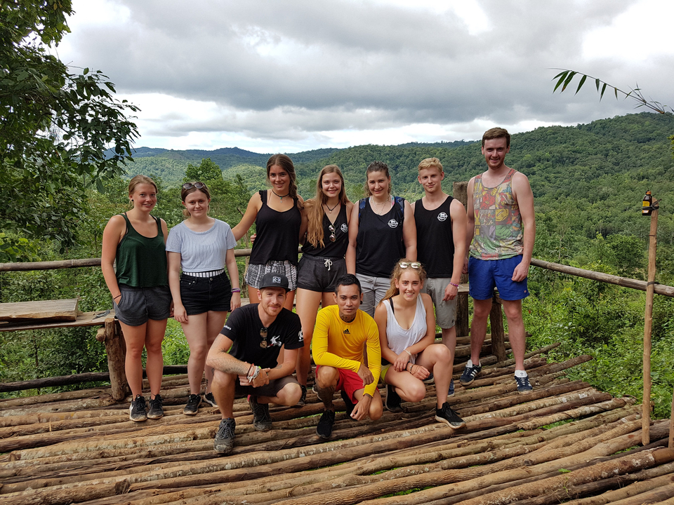 Groupe de personnes posant avec une vue panoramique sur la forêt derrière eux.