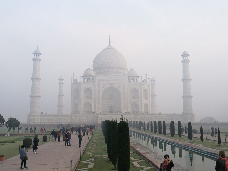Le Taj Mahal dans la brume avec des visiteurs au premier plan.