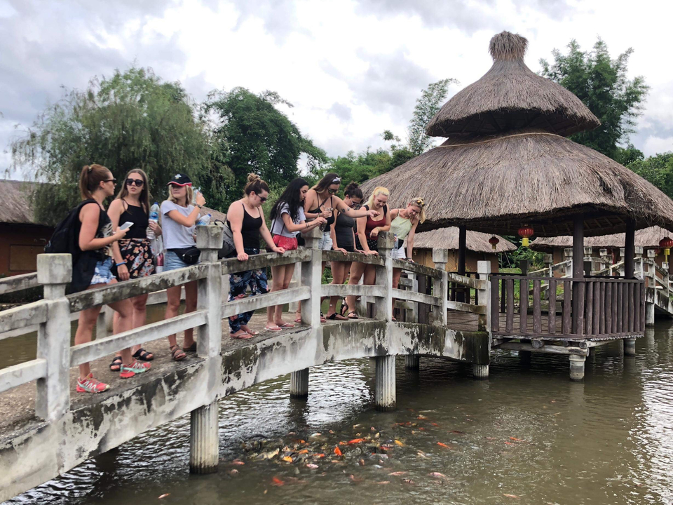 Group of people standing on a bridge, looking down at the water.