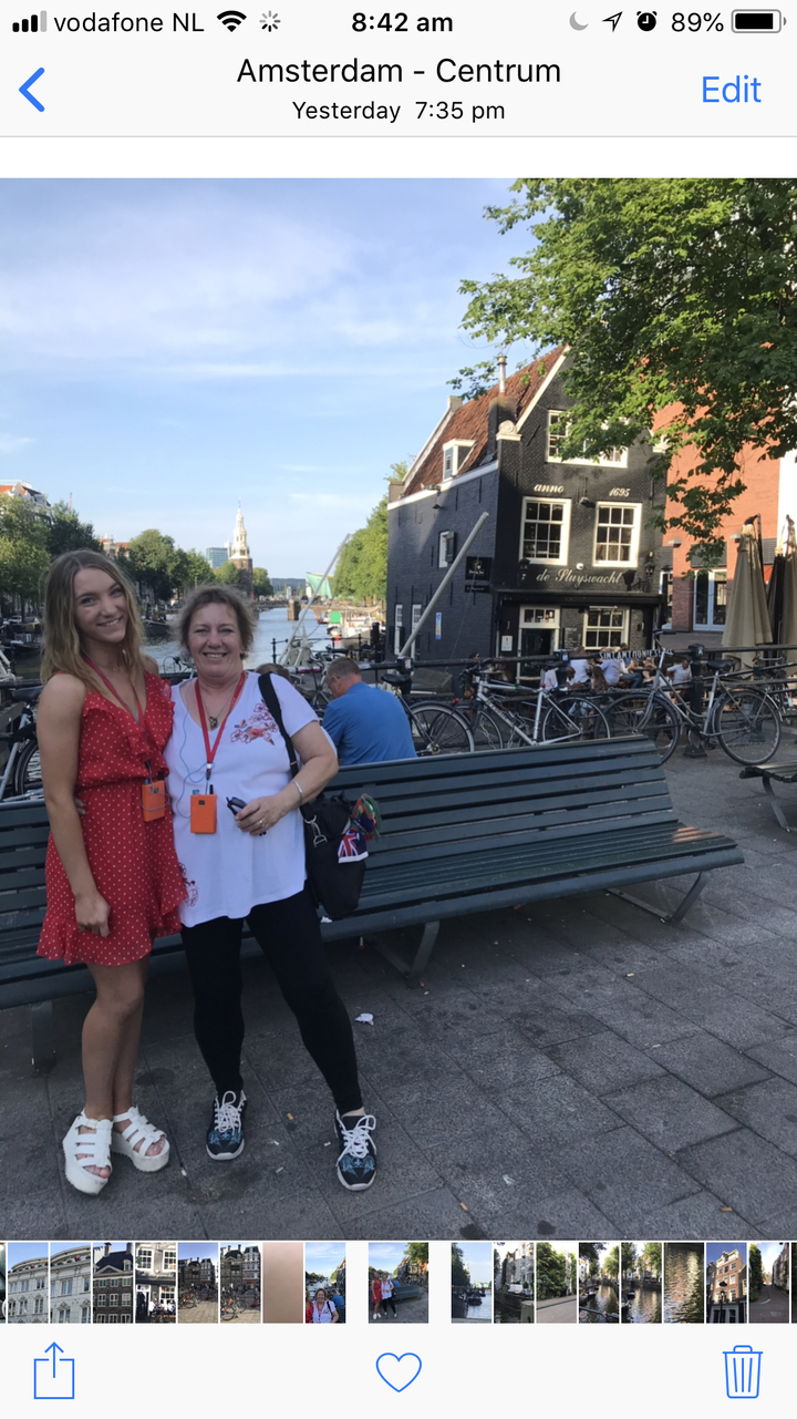 Deux femmes posant près d'un canal avec des vélos et un café en arrière-plan.