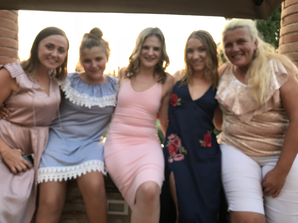 Groupe de femmes posant pour une photo à l'extérieur au coucher du soleil.