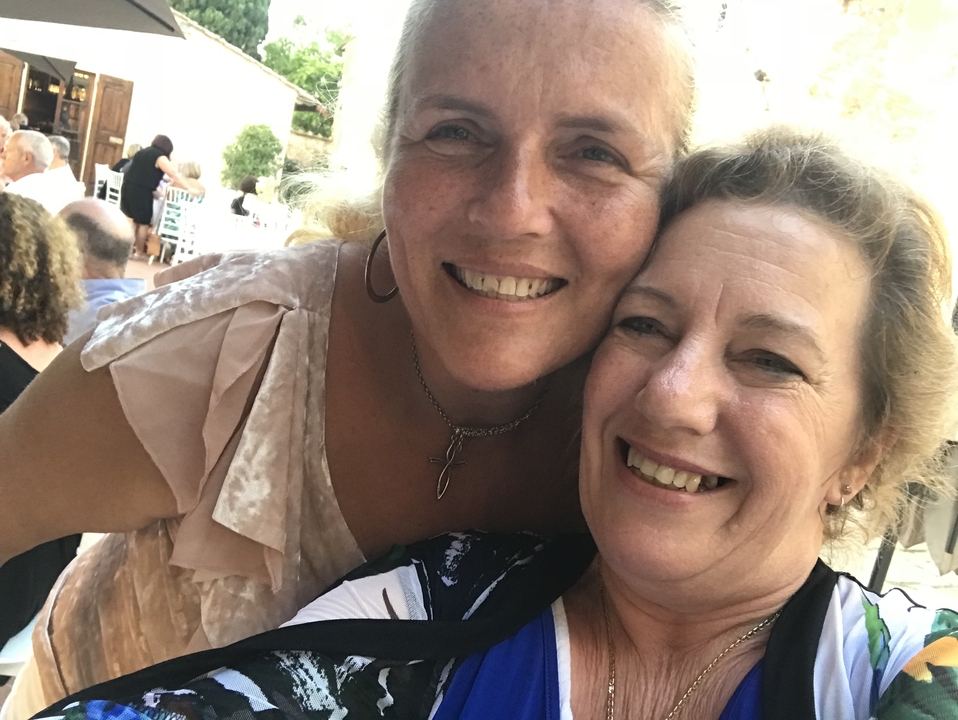 Deux femmes souriantes lors d'un événement social en plein air.