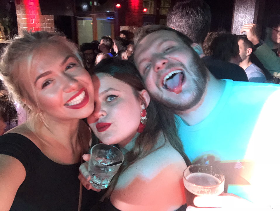 Three people taking a selfie indoors at an event or gathering.