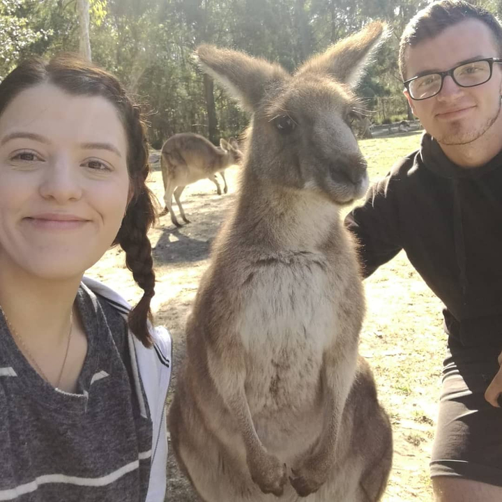 Person posing with a kangaroo in a natural setting.