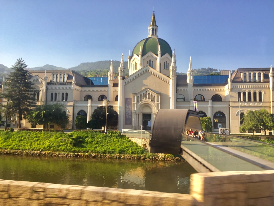 Building by a waterway with mountains in the background.