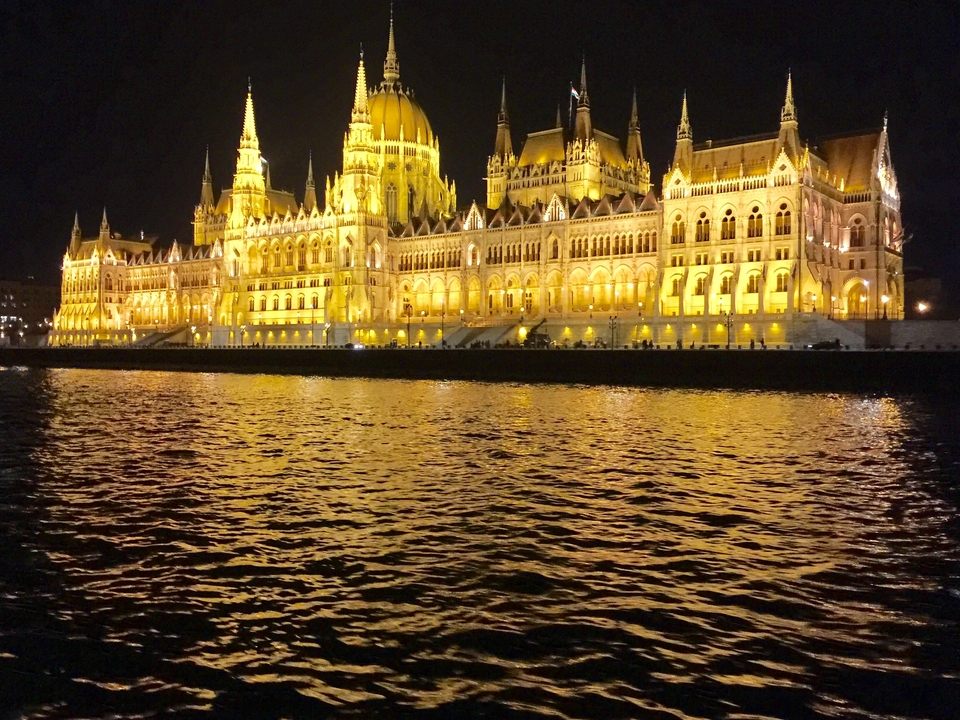 Illuminated historical building reflected on a river at night.
