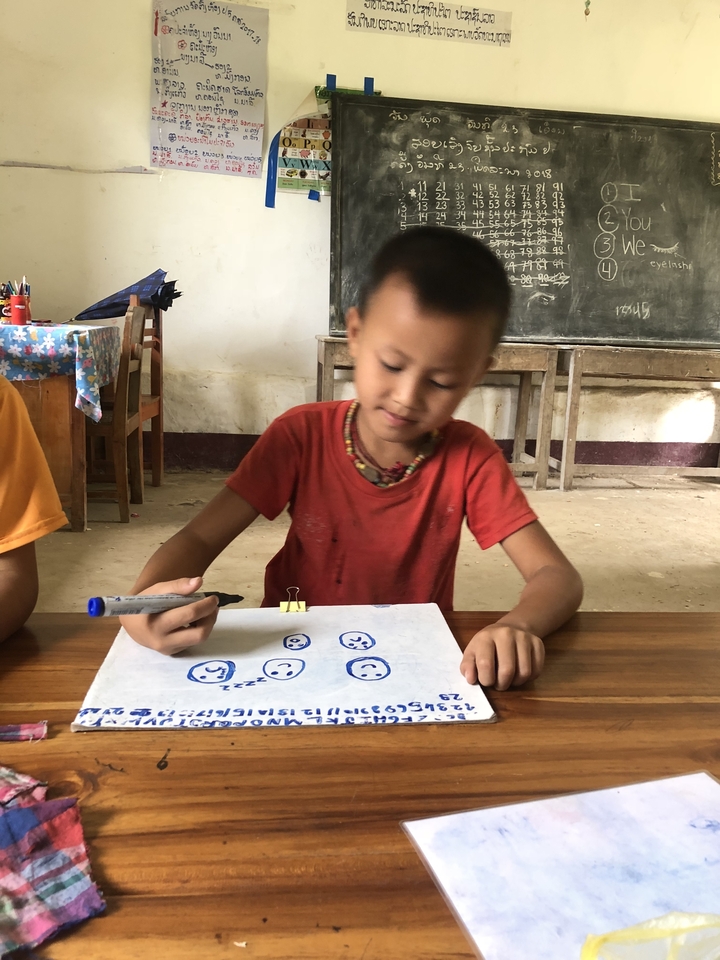 Child drawing on paper in a classroom.