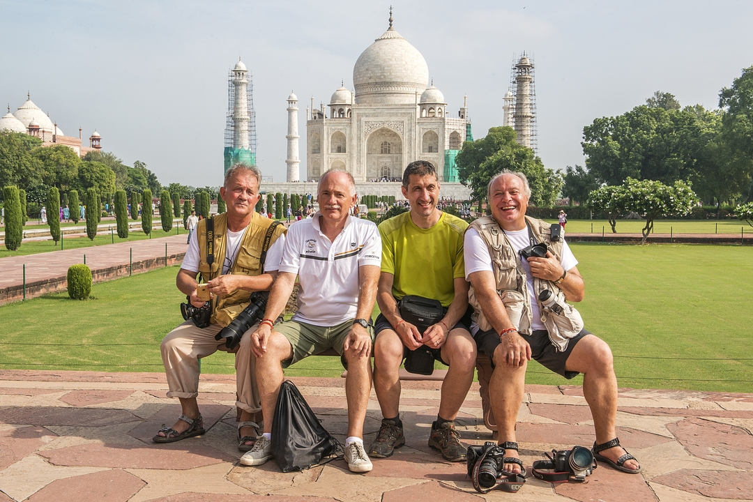 Quatre hommes posant avec des appareils photo dans les jardins du Taj Mahal.