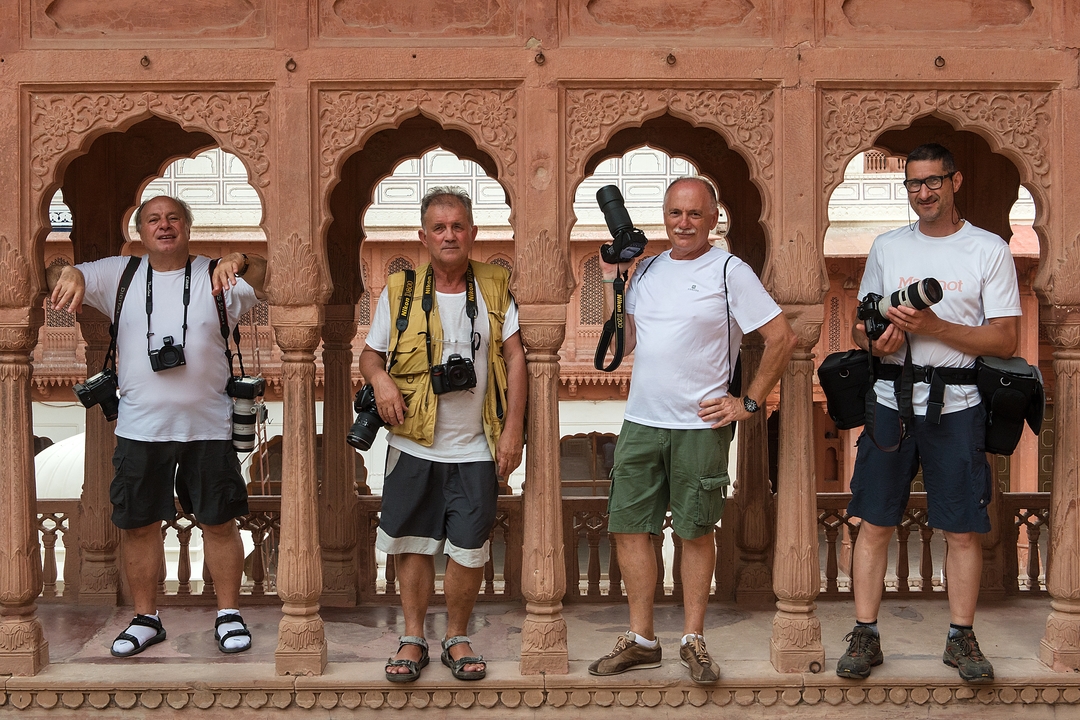 Quatre photographes posant entre des arches décoratives.
