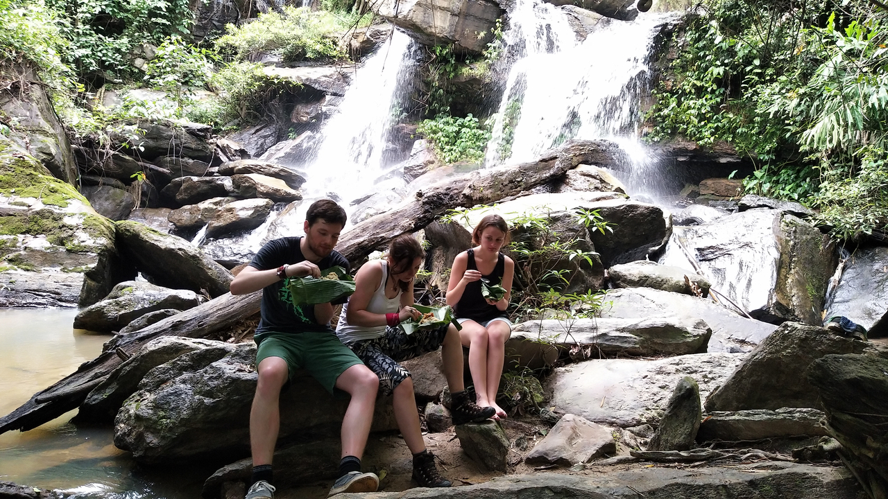 People sitting by a waterfall enjoying a meal.