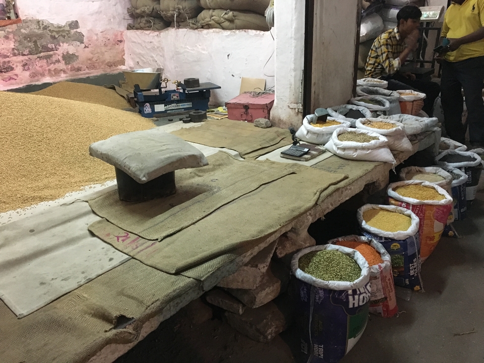 Étal de marché avec des céréales présentées dans des sacs.