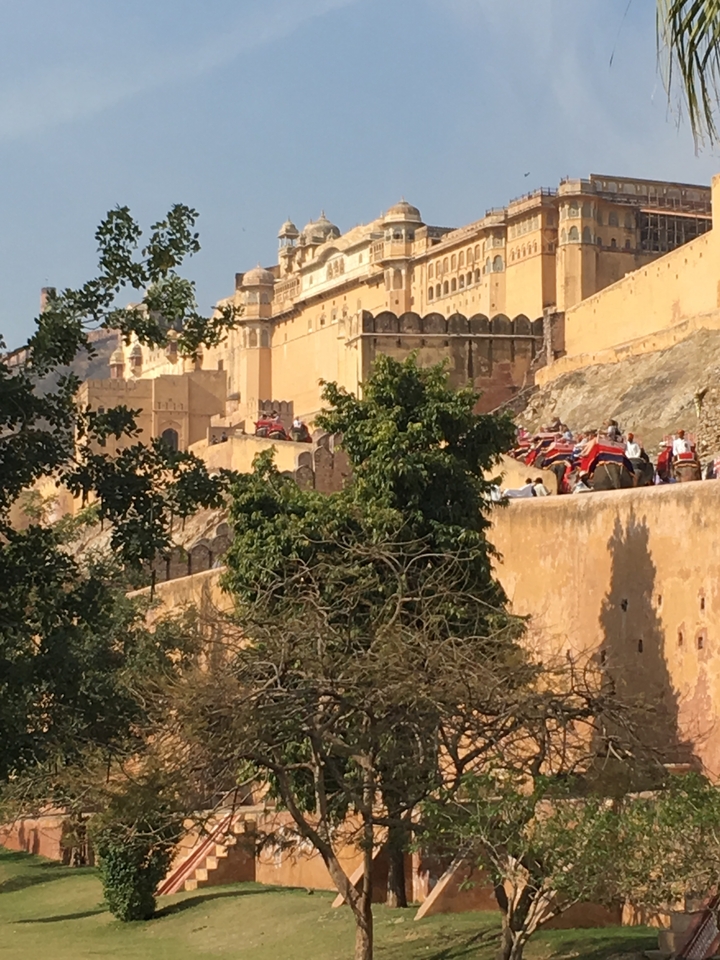 Des gens chevauchant des éléphants près des murs d'un fort.