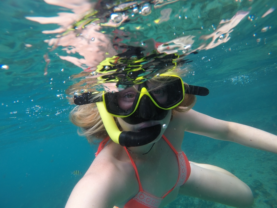 Woman snorkeling underwater, smiling at the camera.