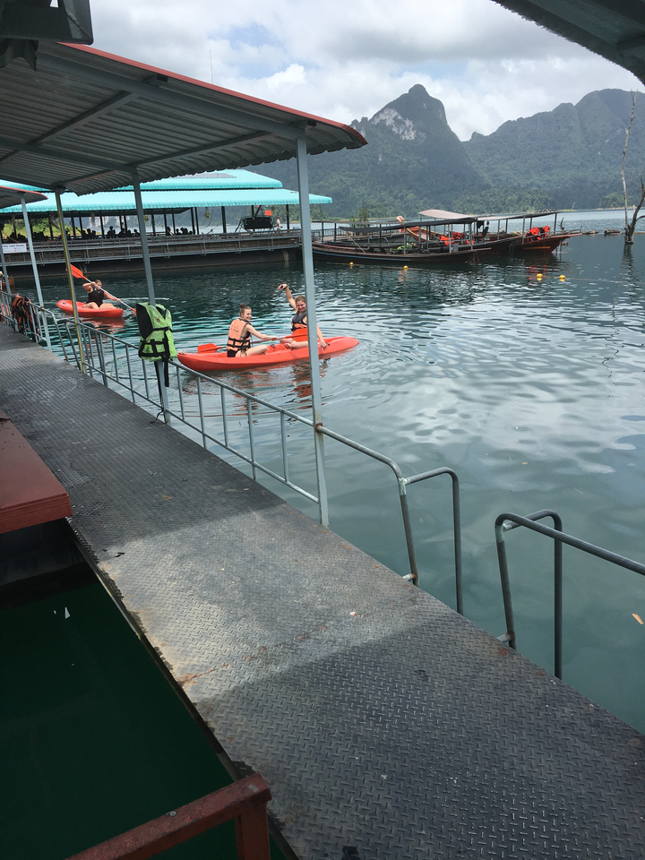 Two people kayaking on clear waters near a dock.