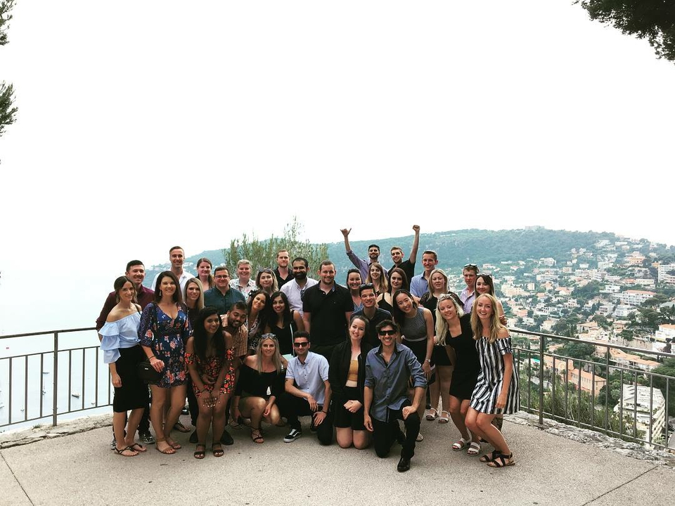 Large group posing on a scenic balcony overlooking a city.