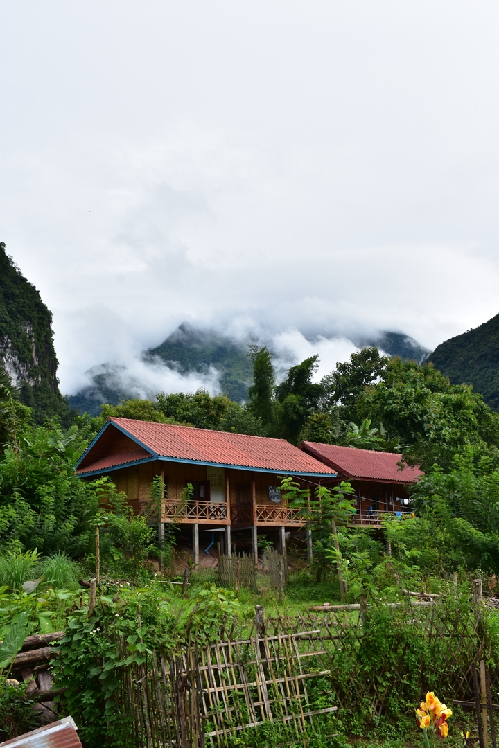 Cloud-covered mountains with red-roofed houses in the foreground.