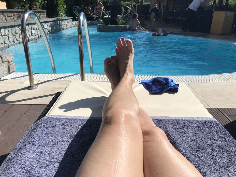 Une personne qui se détend au bord d'une piscine avec les jambes allongées.