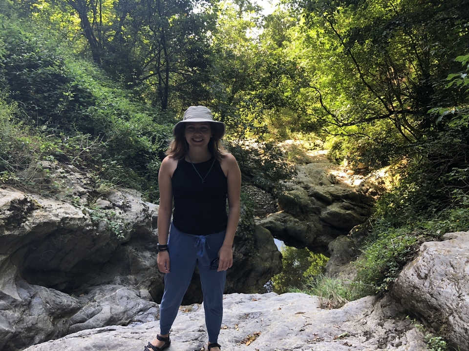 Personne debout sur un sentier rocheux entourée de verdure.