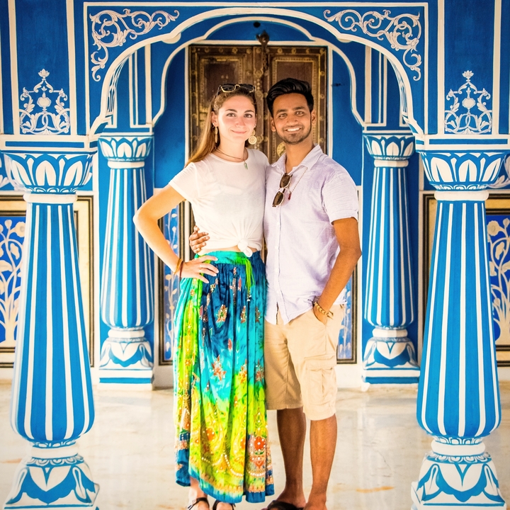 Un couple qui pose devant un bâtiment à colonnes aux couleurs vives.
