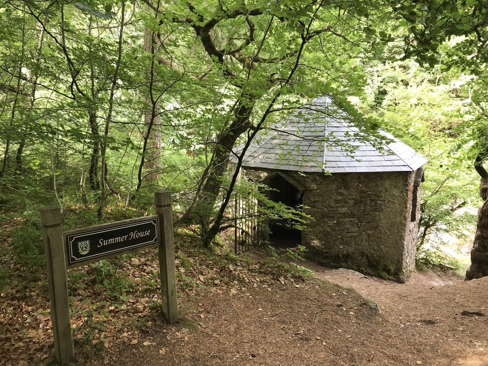 A quaint stone summer house surrounded by dense forest.
