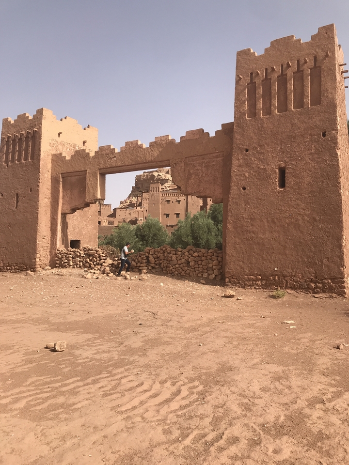 Ruins of an ancient desert building with a person walking through.