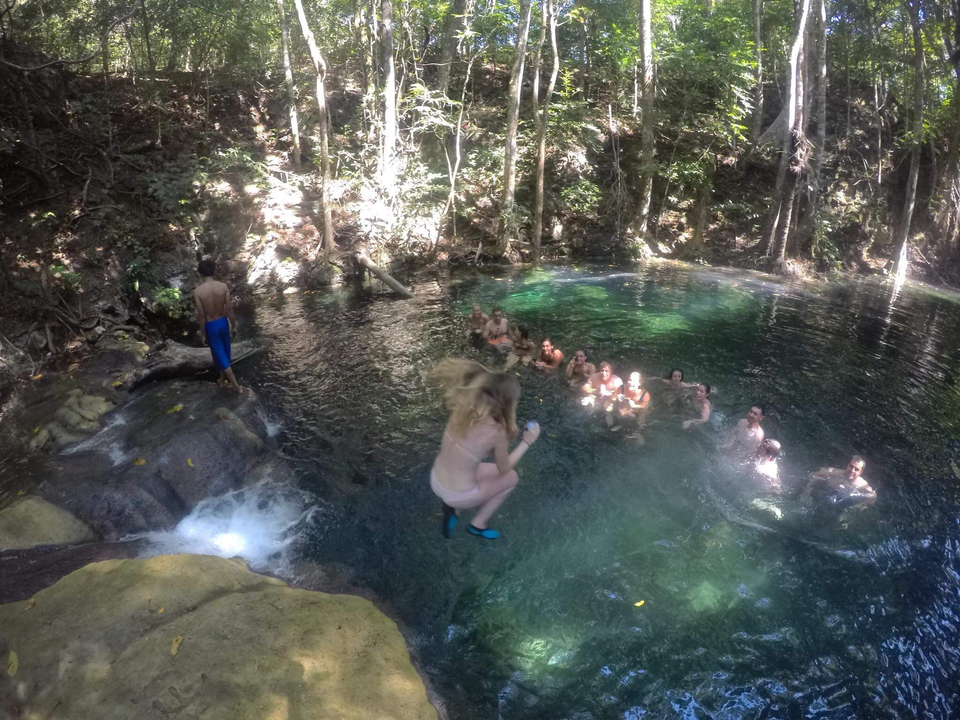 People swimming in a natural pool surrounded by forest.