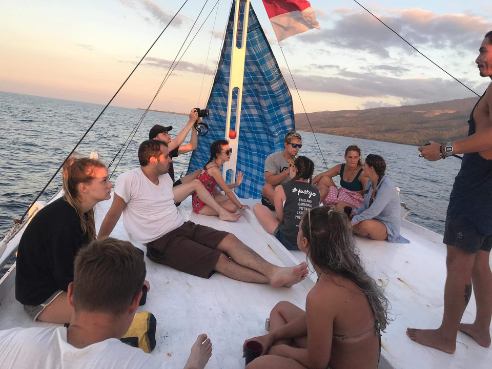 Group of people on a boat at sea during sunset.