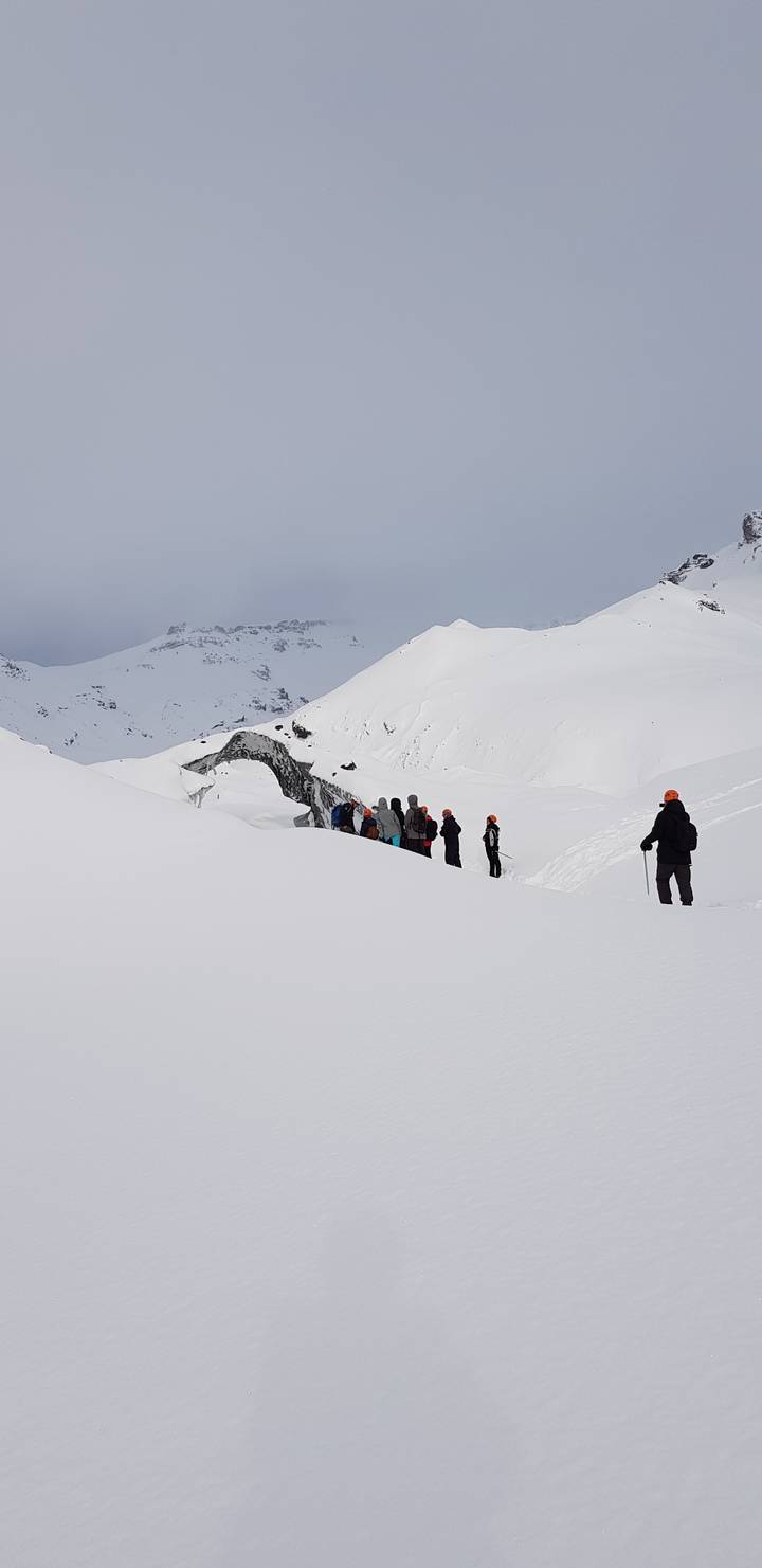 Snow-covered landscape with people hiking in a line.