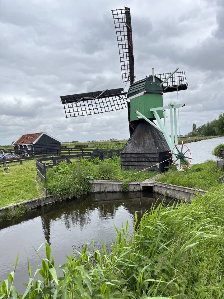Moulin à vent hollandais traditionnel au bord d'un canal dans un cadre rural.