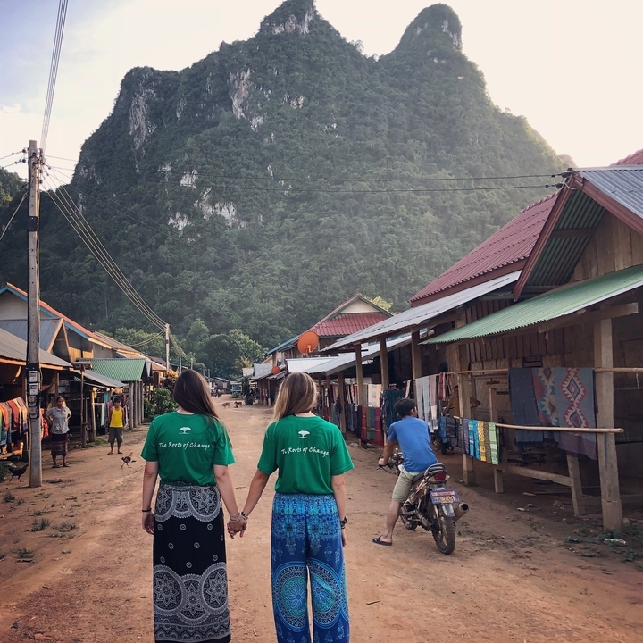Two people walking on a local street with mountain backdrop.