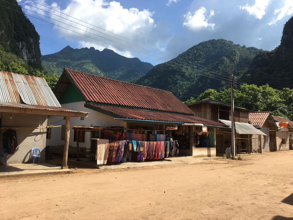 Local village with colorful fabric hanging and mountain in the background.