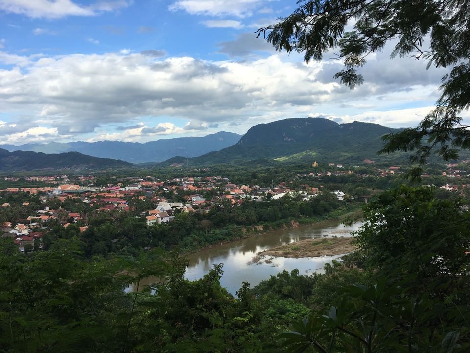 Panoramic view of a town with a river winding through it and mountains in the background.