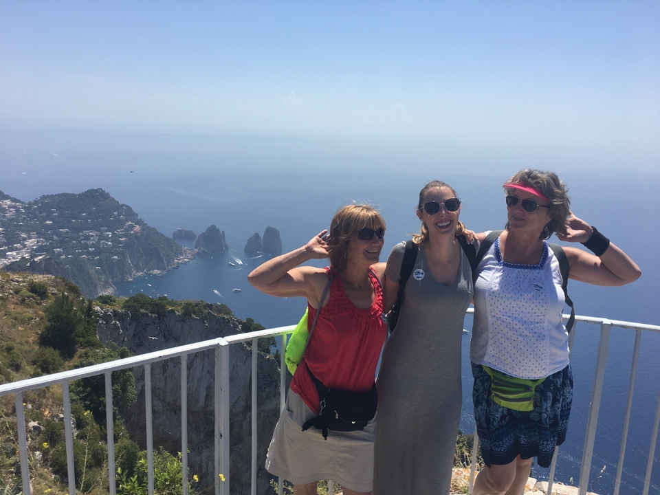 Trois femmes posant sur une plateforme d'observation avec vue sur la mer.