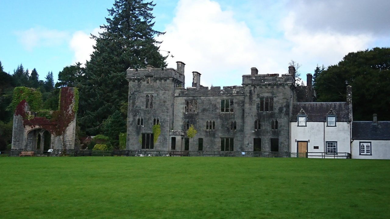 An old stone building with a large tree in the background.