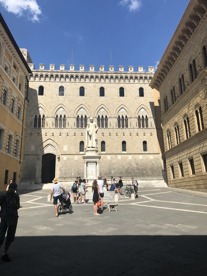A historic building with a statue in a courtyard with people.