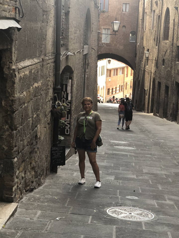 A person standing in a narrow street with rustic buildings.