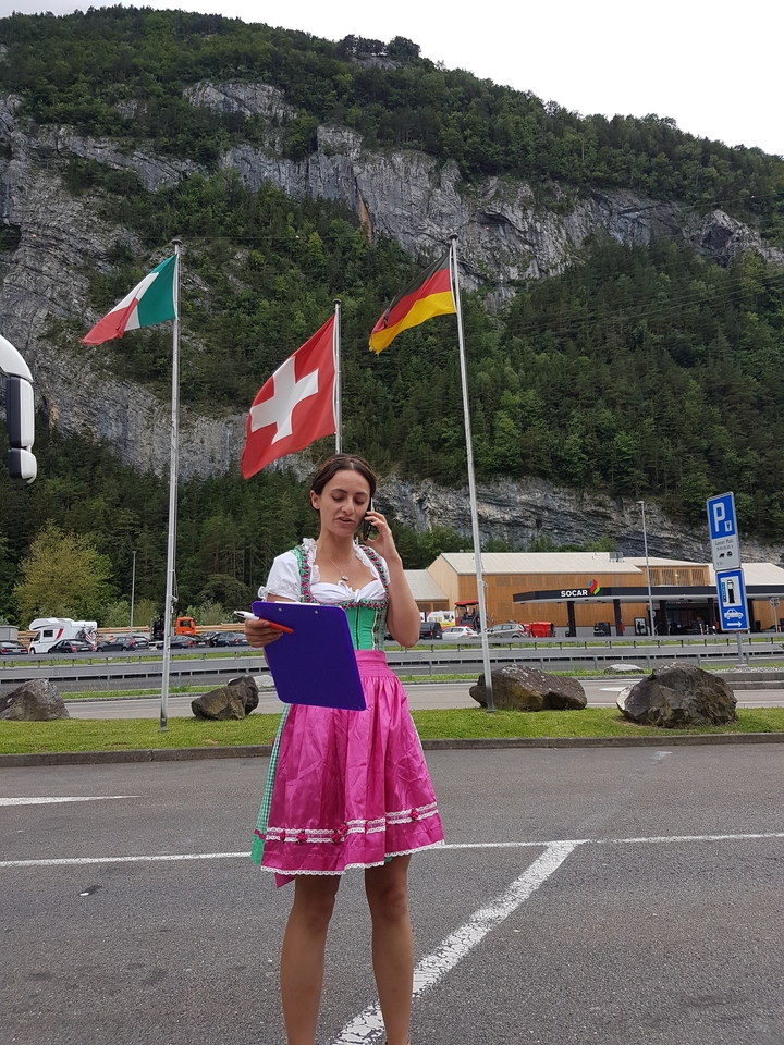 Woman in traditional dress holding a clipboard by flags.