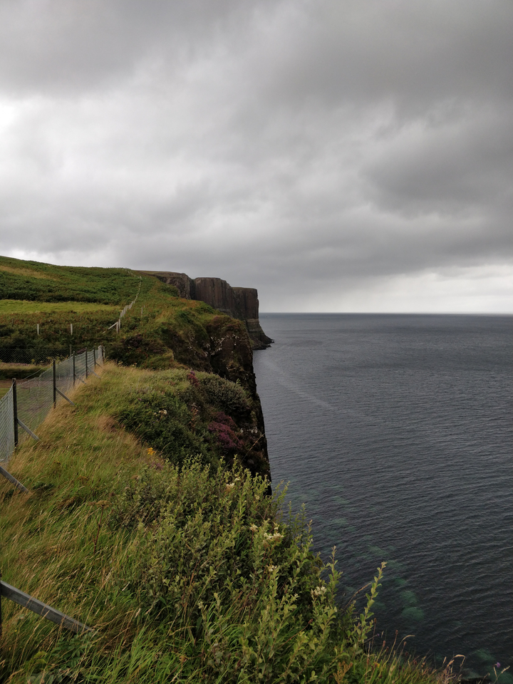 Cliffs overlooking a vast ocean under a cloudy sky.