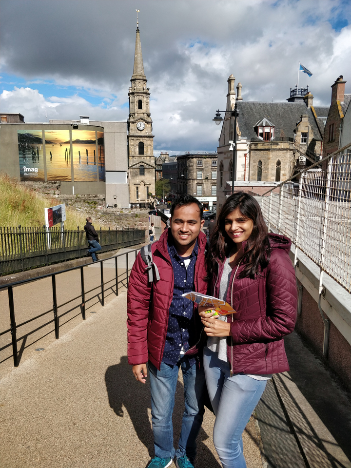 Couple posing in front of historic buildings in a city setting.