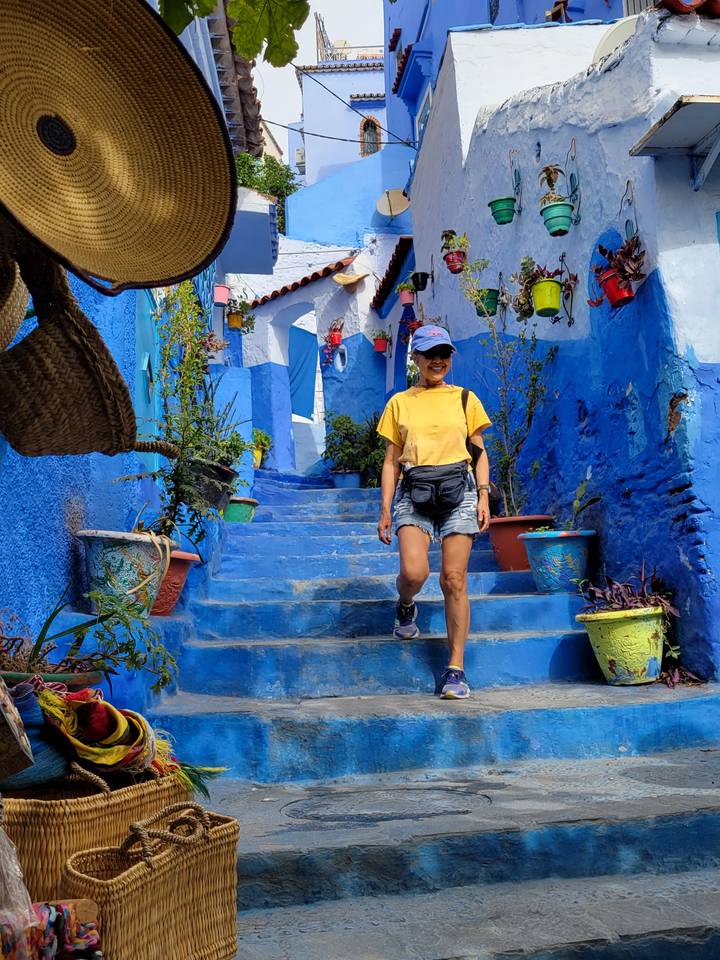 Person walking down a vibrant blue-painted street.