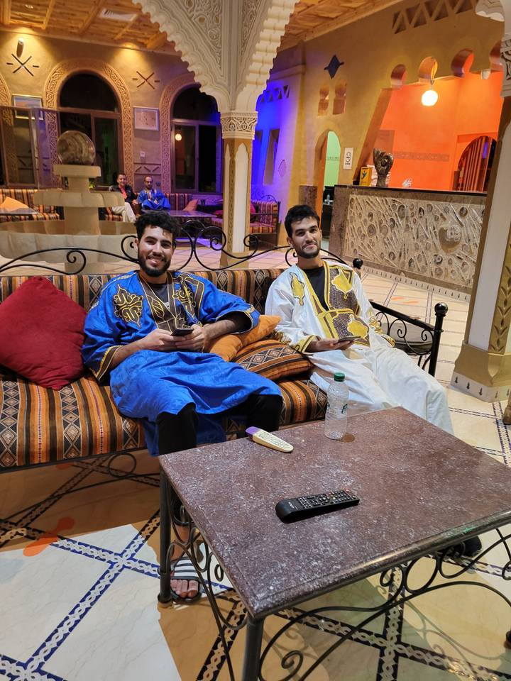 Two people sitting indoors wearing traditional outfits.
